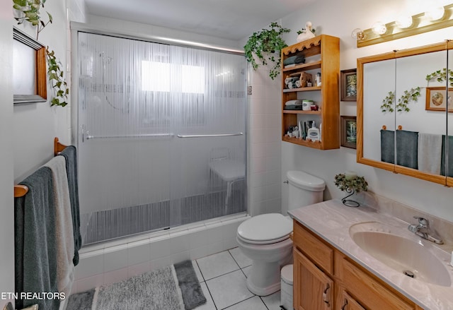 bathroom featuring toilet, a shower with shower door, tile patterned flooring, and vanity