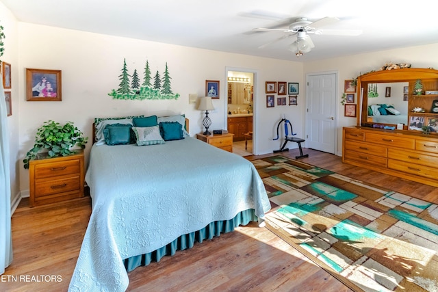 bedroom with ensuite bath, a ceiling fan, and light wood-style floors