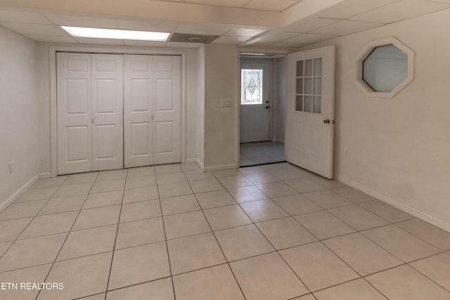 foyer entrance with light tile patterned floors, a paneled ceiling, and baseboards