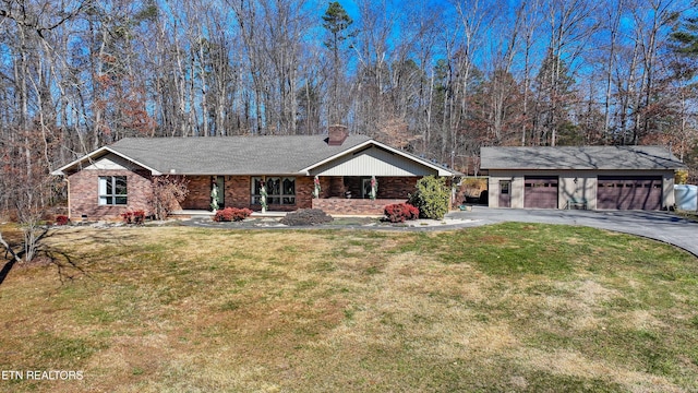 ranch-style house featuring covered porch, a detached garage, a chimney, and a front yard