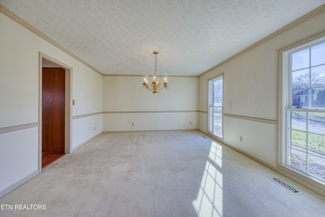 spare room with light colored carpet, a chandelier, a textured ceiling, and a wealth of natural light