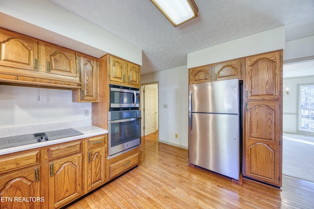 kitchen featuring stainless steel appliances, a textured ceiling, and light hardwood / wood-style flooring