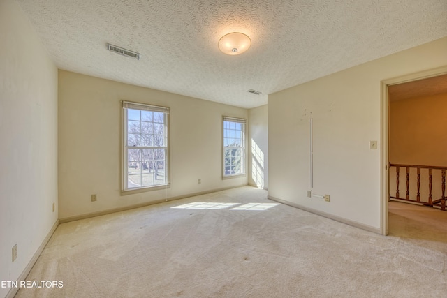 unfurnished room featuring light carpet and a textured ceiling