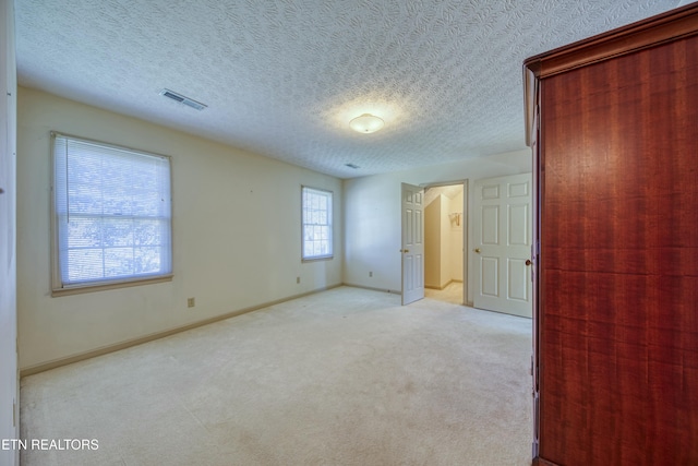 unfurnished bedroom with light colored carpet and a textured ceiling