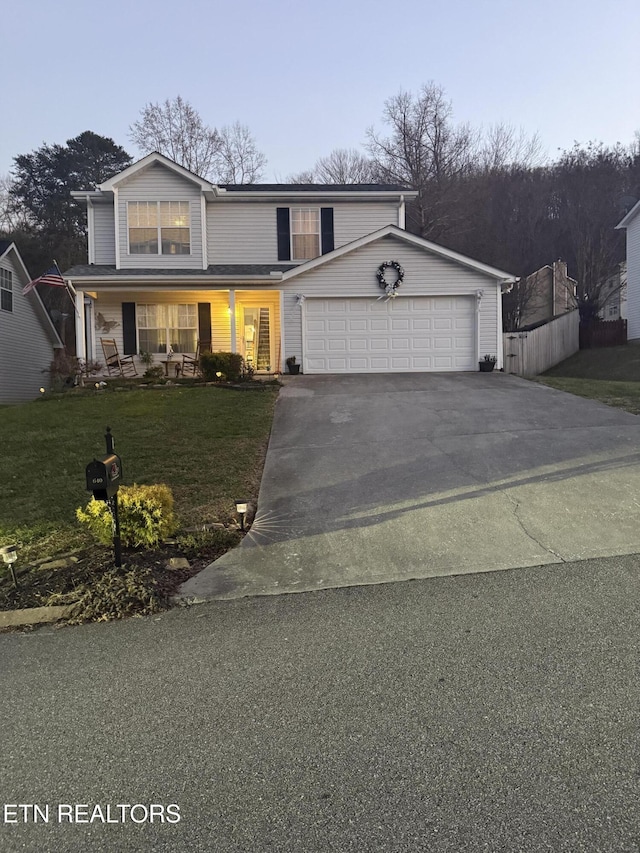 view of property featuring a porch, a garage, and a front lawn