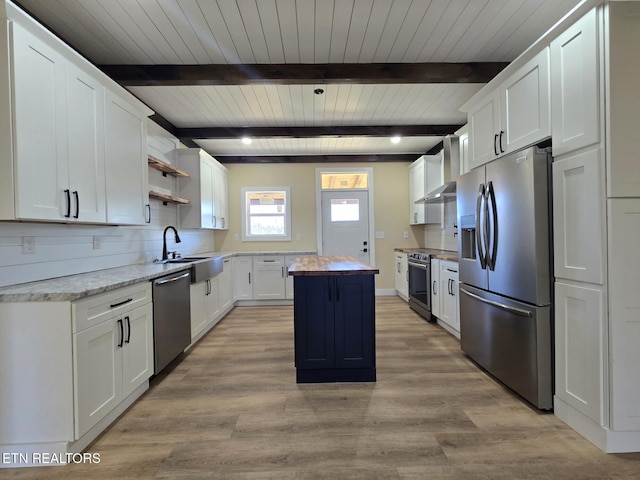 kitchen with light wood-style flooring, a kitchen island, white cabinets, appliances with stainless steel finishes, and open shelves