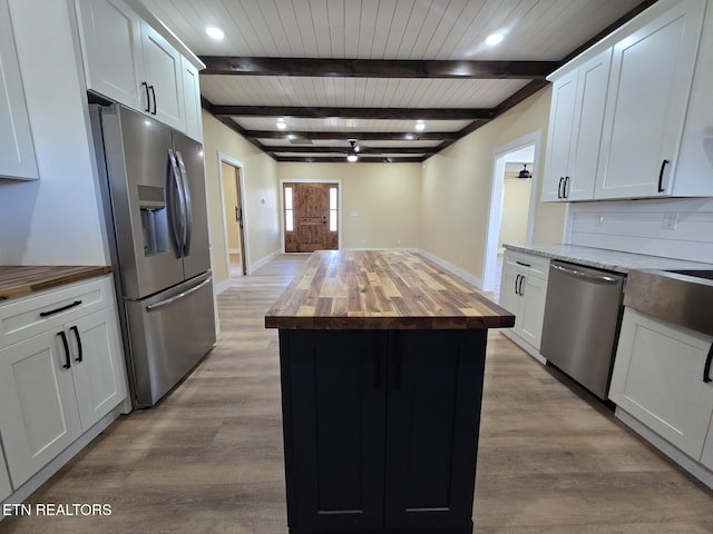 kitchen with wooden counters, appliances with stainless steel finishes, white cabinetry, and light wood-style floors