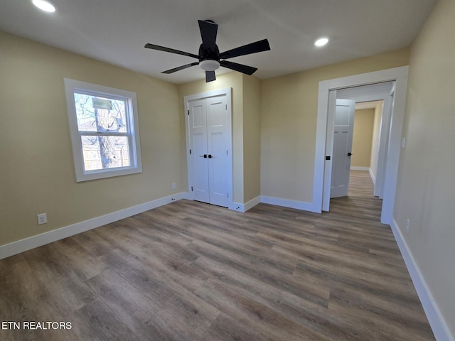 unfurnished bedroom featuring recessed lighting, a closet, ceiling fan, wood finished floors, and baseboards