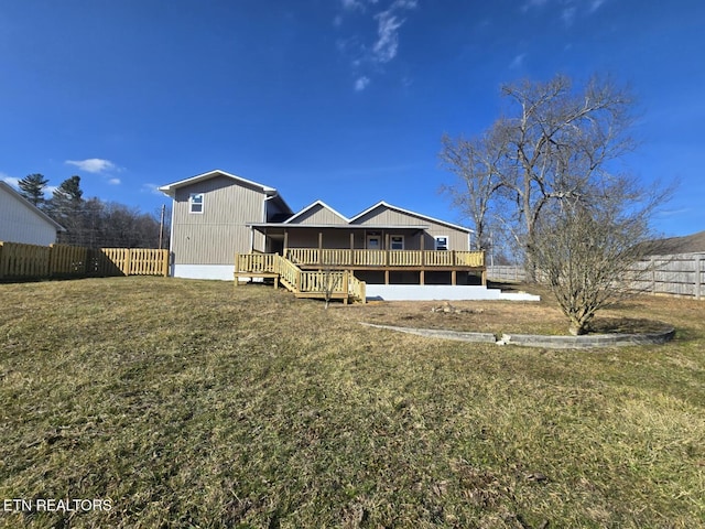 rear view of property featuring fence, a lawn, and a wooden deck