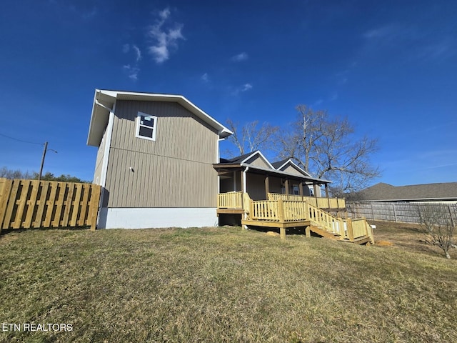 rear view of house with fence, a deck, and a yard