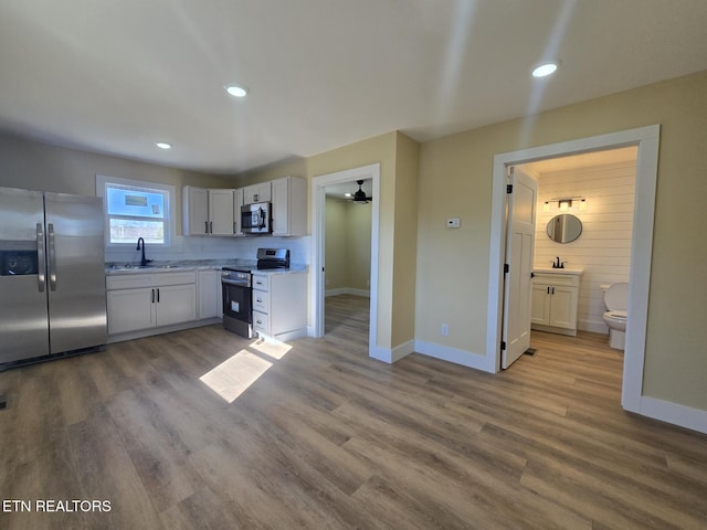 kitchen featuring appliances with stainless steel finishes, a sink, light wood-style floors, and white cabinets