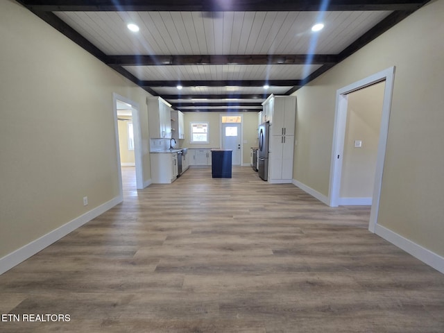 interior space with light wood-style floors, baseboards, beamed ceiling, and recessed lighting