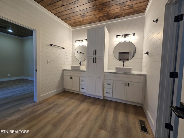 bathroom with double vanity, visible vents, a sink, wood finished floors, and wooden ceiling