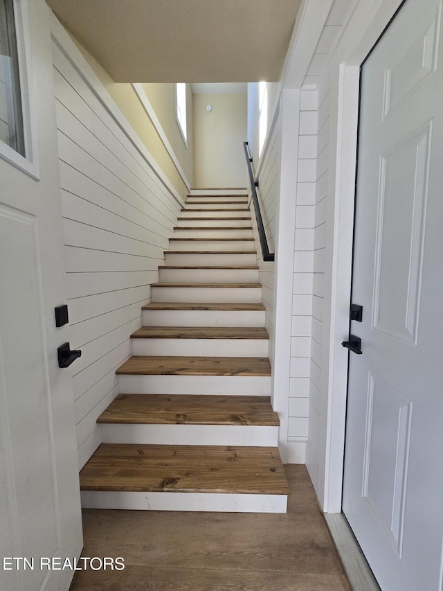 staircase with wood walls and wood finished floors