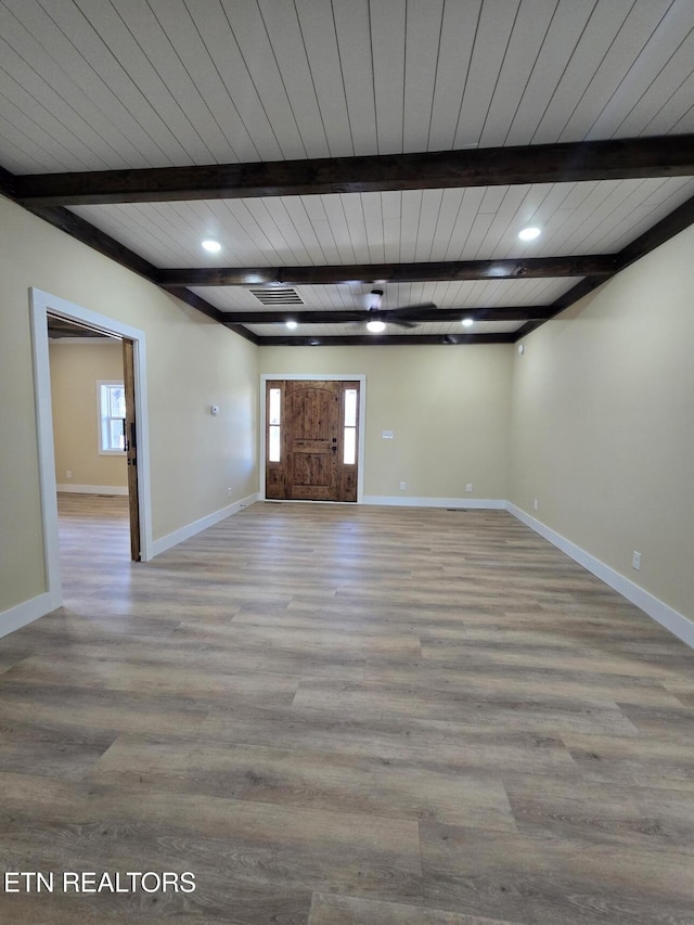 interior space featuring light wood-style floors, beam ceiling, visible vents, and baseboards