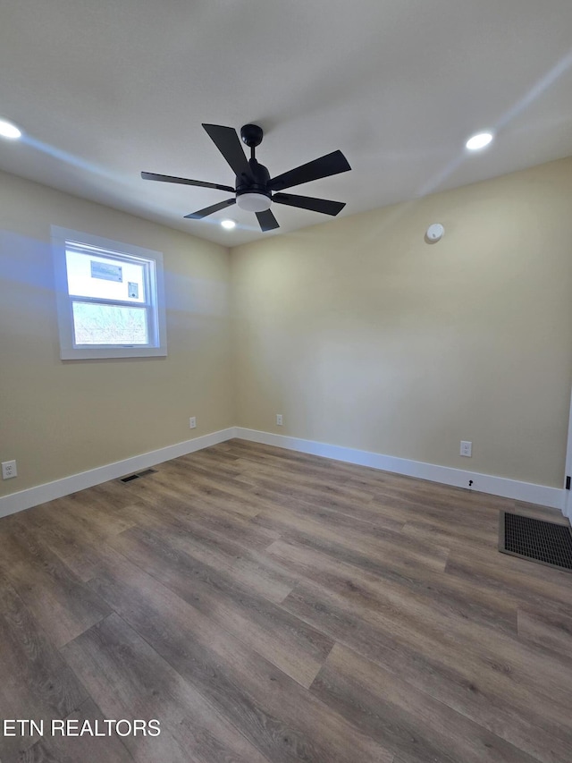 unfurnished room with dark wood-style flooring, visible vents, and baseboards