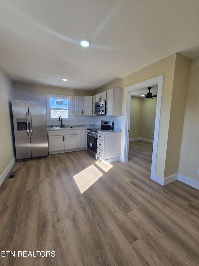 kitchen with light countertops, appliances with stainless steel finishes, a sink, and white cabinets