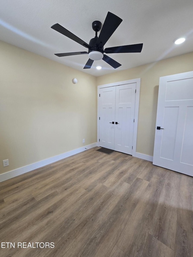 unfurnished bedroom featuring baseboards, a ceiling fan, wood finished floors, a closet, and recessed lighting