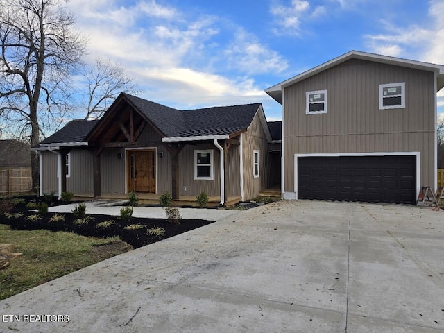 view of front of home with a garage, a shingled roof, and concrete driveway