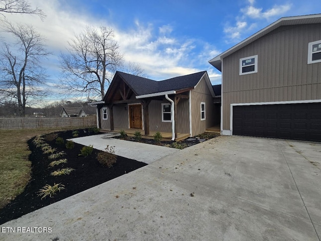 view of front of house featuring driveway, an attached garage, and fence