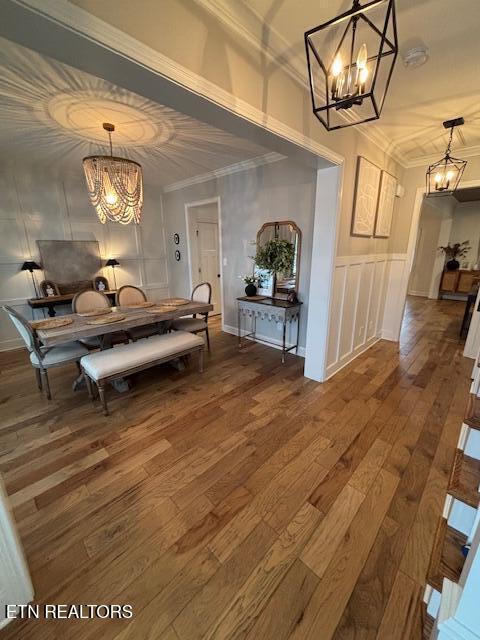 hallway with a chandelier, dark wood-type flooring, and ornamental molding