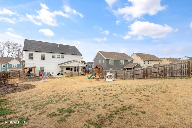 rear view of property featuring a fenced backyard, a residential view, a playground, and a lawn