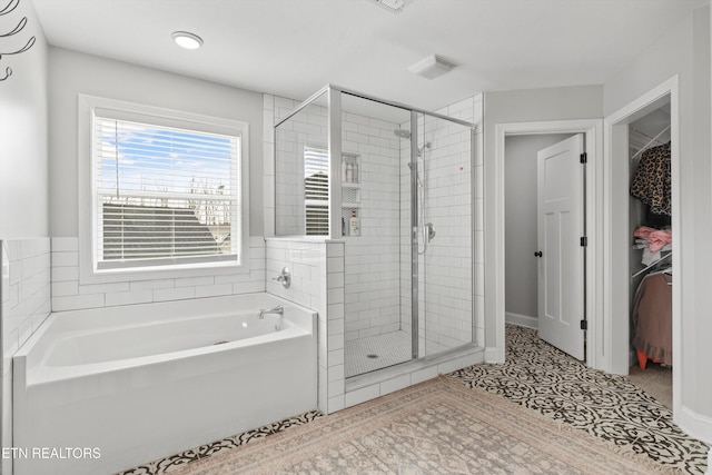 bathroom with a shower stall, tile patterned floors, visible vents, a walk in closet, and a bath