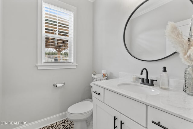 half bathroom featuring a wealth of natural light, toilet, vanity, and baseboards