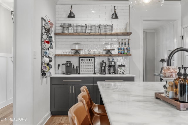 bar with indoor bar, light wood finished floors, crown molding, and decorative backsplash