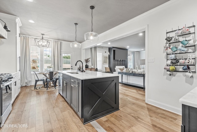 kitchen with light countertops, light wood finished floors, stainless steel electric range, and a sink