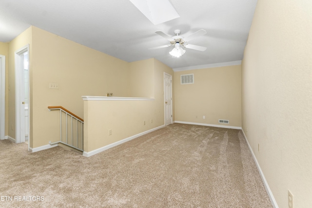 carpeted spare room with a skylight and ceiling fan