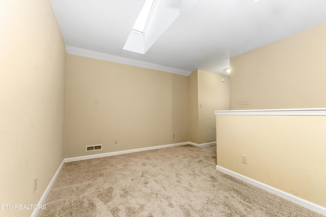 unfurnished room with light colored carpet and a skylight