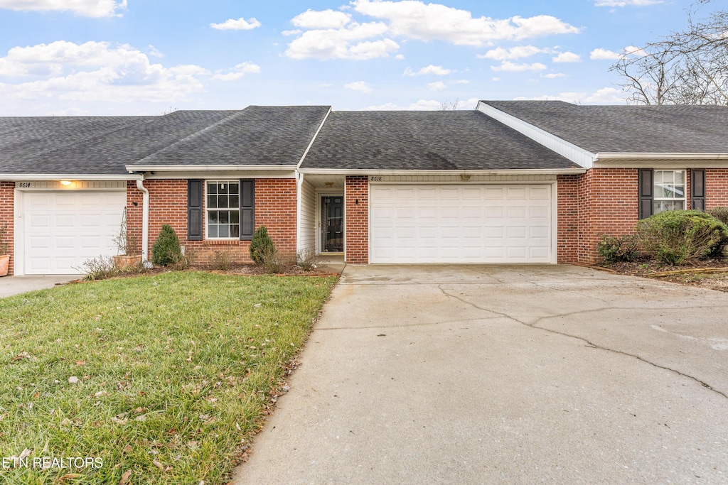 ranch-style home featuring a garage and a front lawn