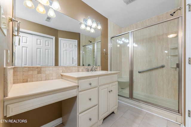 bathroom featuring tile patterned flooring, vanity, a shower with shower door, and tasteful backsplash