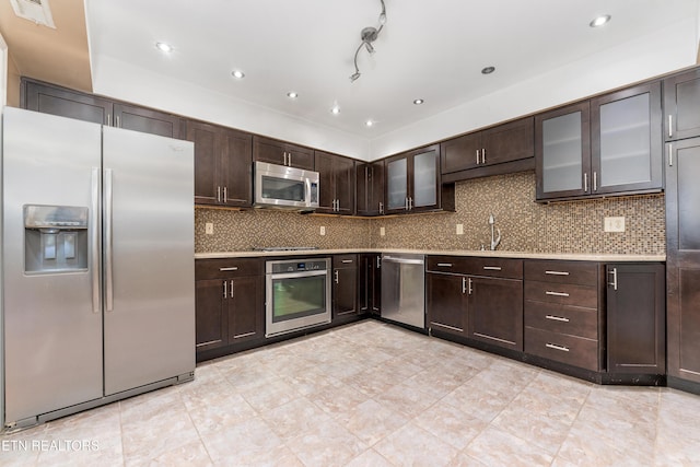 kitchen with dark brown cabinetry, stainless steel appliances, sink, and decorative backsplash