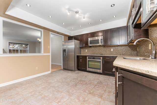 kitchen featuring appliances with stainless steel finishes, sink, dark brown cabinets, and backsplash