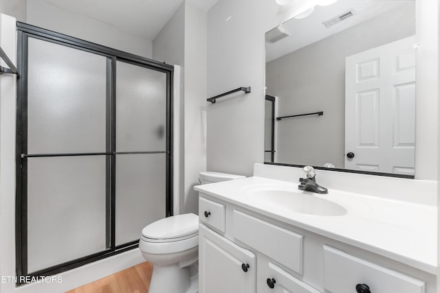 bathroom featuring vanity, hardwood / wood-style floors, a shower with shower door, and toilet