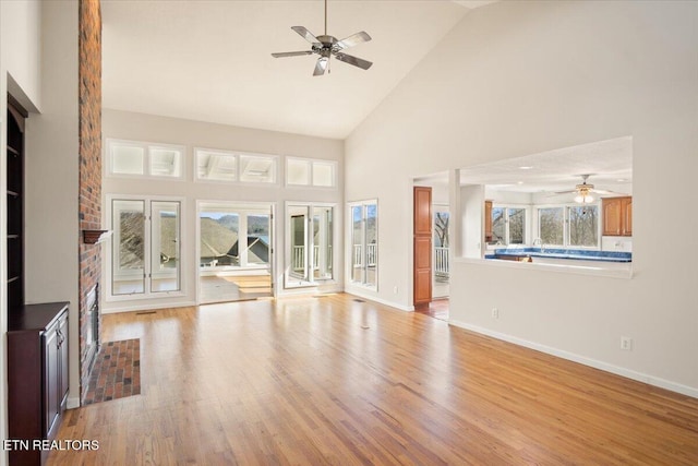 unfurnished living room featuring baseboards, high vaulted ceiling, and light wood-style flooring