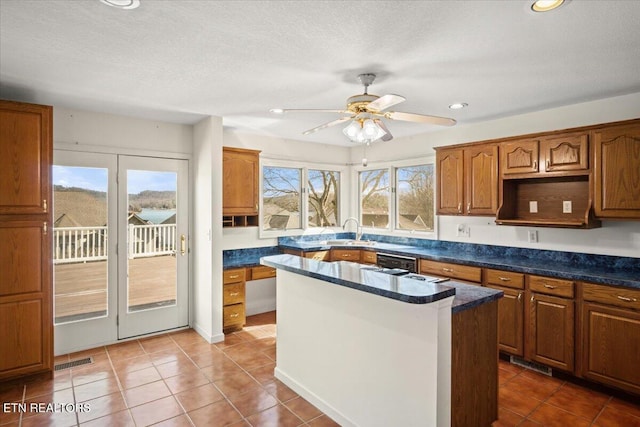 kitchen featuring tile patterned flooring, a center island, visible vents, and a sink