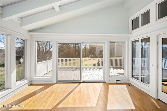 unfurnished sunroom featuring vaulted ceiling with beams and a healthy amount of sunlight