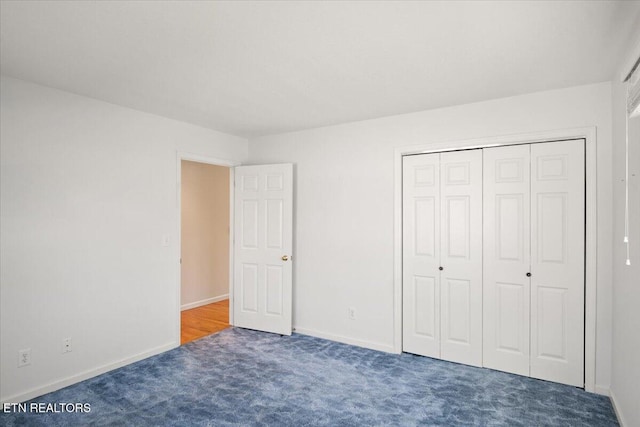 unfurnished bedroom with carpet flooring, baseboards, and a closet