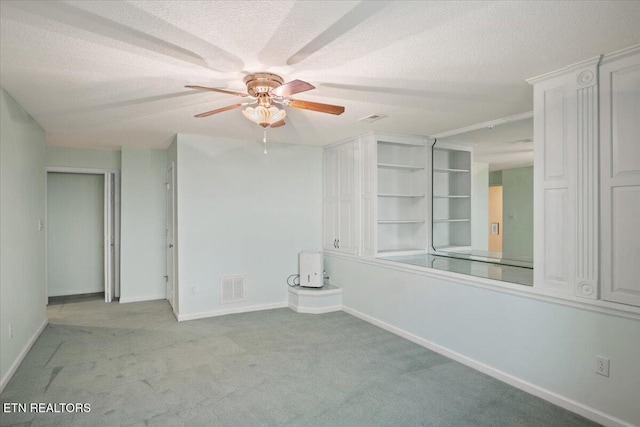 empty room featuring visible vents, a ceiling fan, a textured ceiling, carpet floors, and baseboards