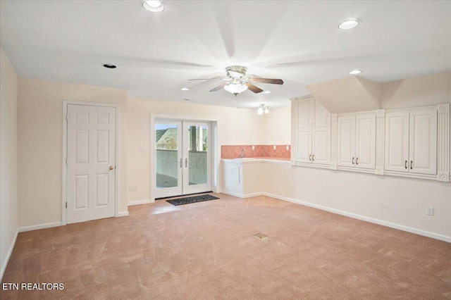 empty room with light carpet, ceiling fan, french doors, and baseboards