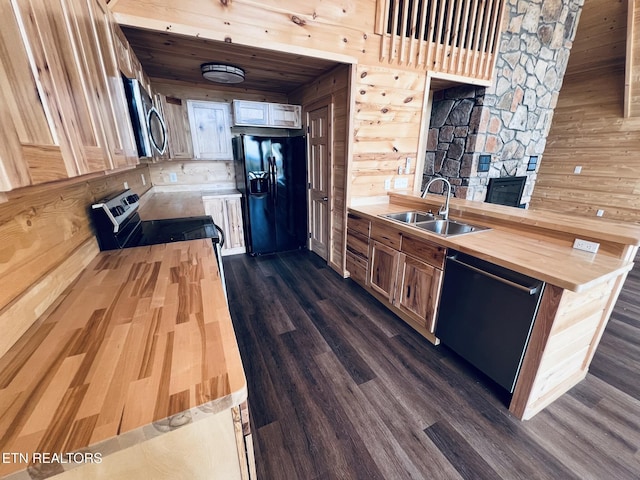 kitchen featuring butcher block countertops, sink, dark hardwood / wood-style floors, wooden walls, and black appliances