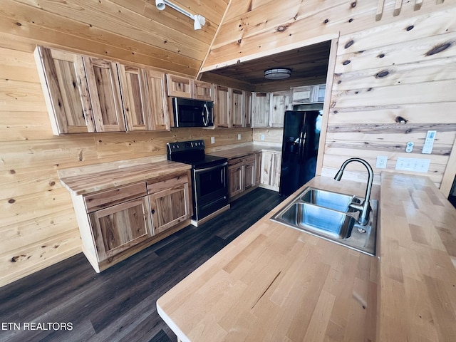 kitchen with vaulted ceiling, wooden walls, sink, dark hardwood / wood-style flooring, and black appliances