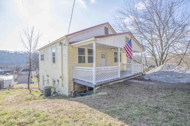 view of front of house featuring central AC unit, a front yard, and covered porch