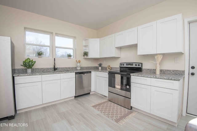 kitchen featuring sink, light stone counters, light hardwood / wood-style flooring, stainless steel appliances, and white cabinets