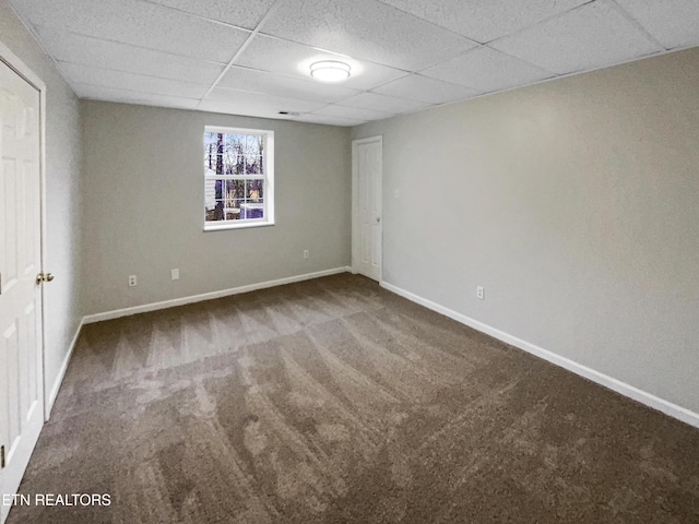 carpeted empty room featuring a paneled ceiling