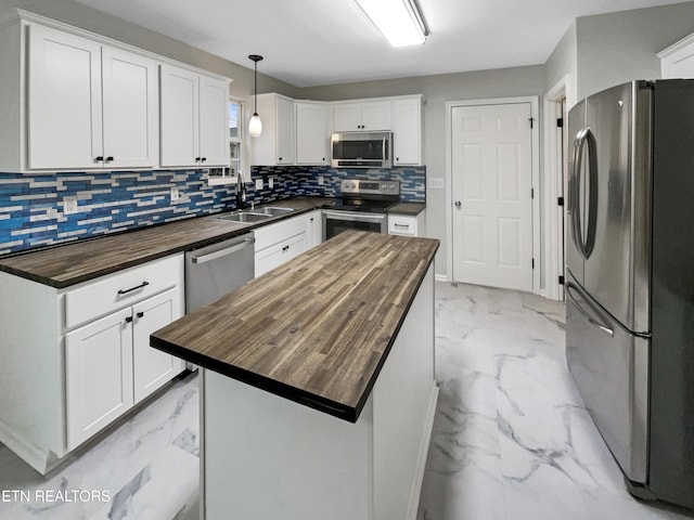 kitchen with a kitchen island, white cabinetry, appliances with stainless steel finishes, and butcher block counters