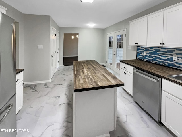 kitchen with appliances with stainless steel finishes, a center island, white cabinets, and wood counters